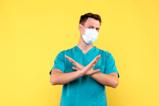 成人黄墙上戴着无菌口罩的男医生的正视图专业情绪微笑