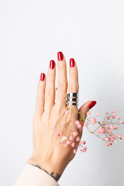 开花柔美温柔的照片 女人手上戴着大戒指 红色的指甲 手上拿着可爱的粉色干花博客叶美甲