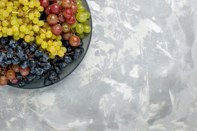 橄榄顶视图新鲜葡萄多汁醇厚的水果盘内放在白色桌上水果醇厚的果汁酒新鲜可食用的水果顶部葡萄酒