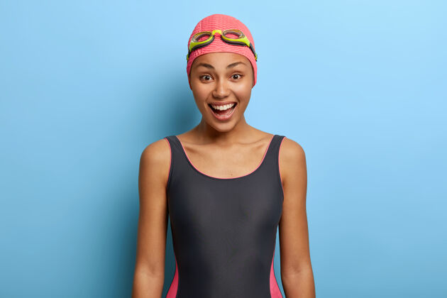 凝视积极的黑人女游泳教练穿着泳衣 泳衣和护目镜高兴爱好服装
