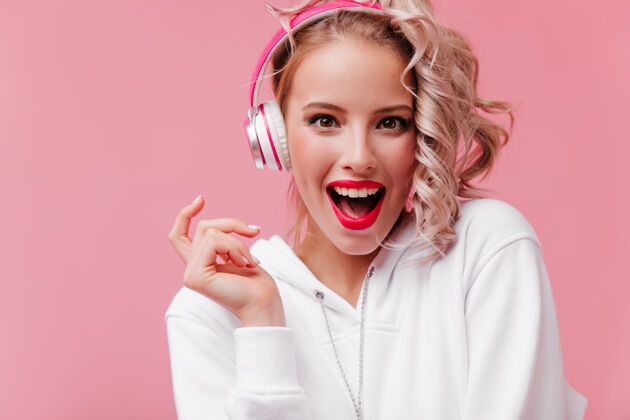 多彩年轻女子摆姿势 通过她的粉红色耳机听音乐肖像奢华时尚