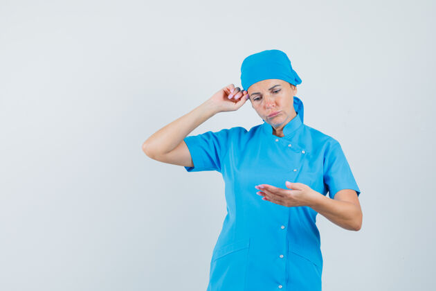 年轻人女医生假装穿着蓝色制服看手机 神情沉思 前视图诊所长相手机