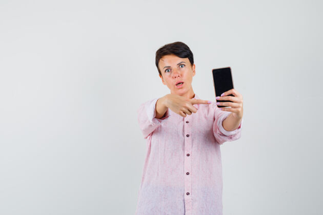 女人身穿粉色衬衫的女性指着手机 神情迷惑不解 前视图诊所手机成人