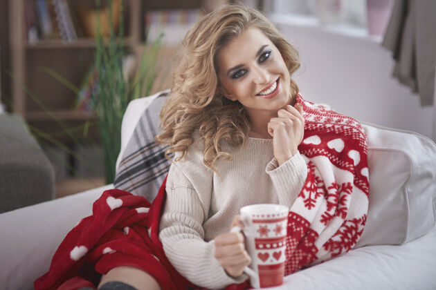 牙齿微笑年轻的金发女人在喝热巧克力房子圣诞装饰品杯子