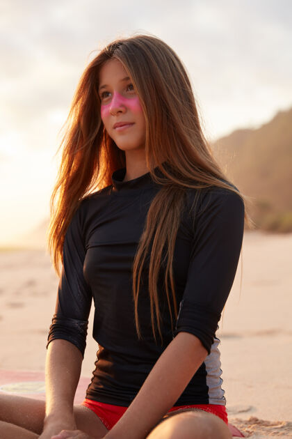 大海梦幻般的年轻女子穿着泳装 戴着粉色的锌面罩 盘腿坐在沙滩上 思考着什么 专注于远方人 生活方式和极限运动理念青少年泳装户外