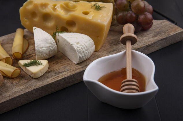 蜂蜜侧视图的奶酪与葡萄和蜂蜜的立场上的黑色背景类型黑美食观点