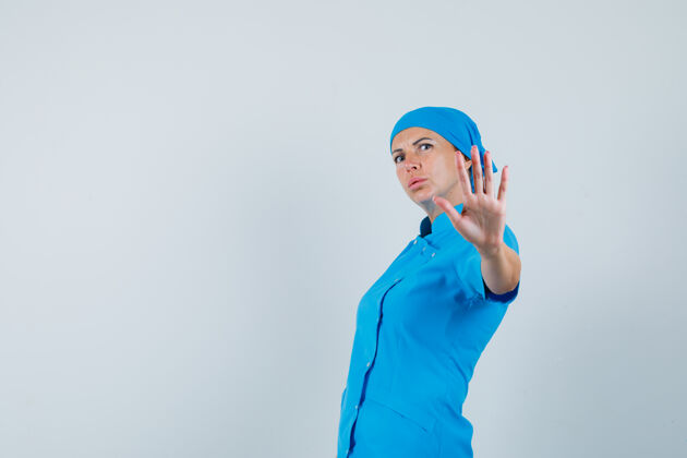 焦虑身穿蓝色制服的女医生展示停车姿势 表情焦急 俯视前方女人表演手势