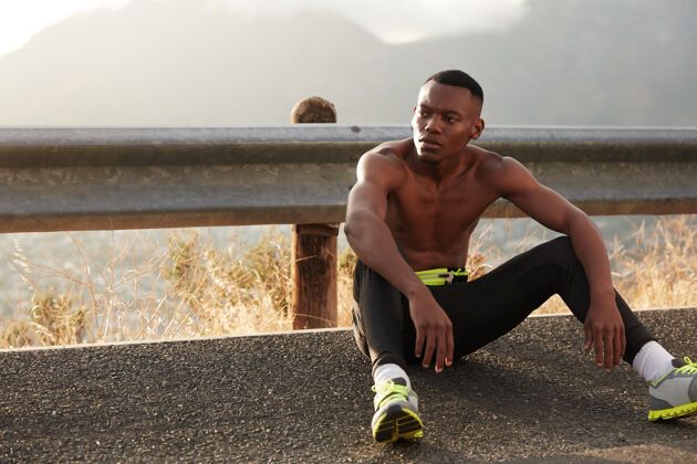 环境充满活力的沉思黑人男子坐在户外柏油路上 完成跑步或准备体育比赛 穿着运动鞋 过着健康的生活方式 把目光放在一边有氧运动户外肌肉民族