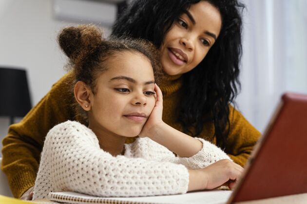 姐妹笑脸少女帮助妹妹在网上学习期间与平板电脑知识学习小