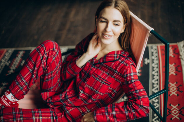 睡衣穿着圣诞睡衣坐在椅子上的年轻女人人放松时尚