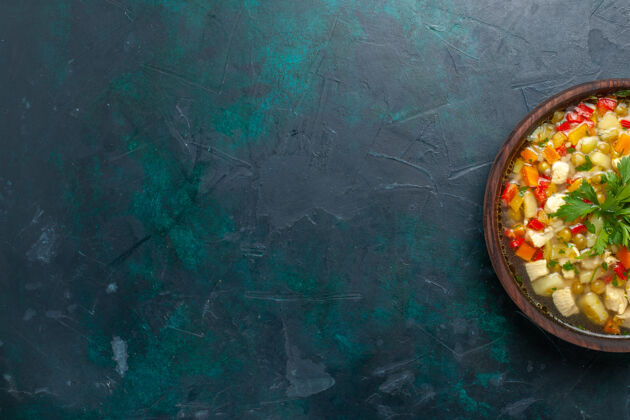 生的俯瞰美味的蔬菜汤 里面有不同的配料 棕色的锅 深蓝色的桌子 汤 蔬菜酱 食物 热的食物帽子汤旧的
