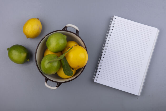 灰色顶视图复制空间柠檬与酸橙在平底锅与记事本在灰色背景新鲜视图空间
