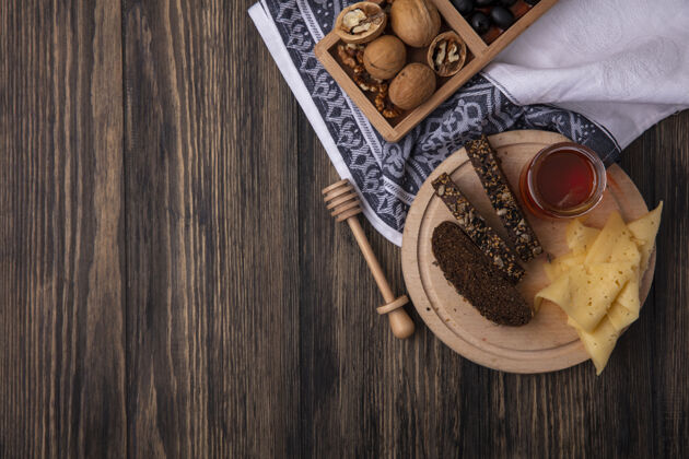 自然顶视图复制空间蜂蜜在一个罐子与黑面包和奶酪的立场上与核桃木背景食物黑色甜味
