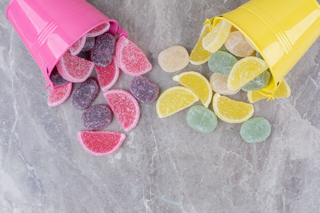 粉色黄色和粉色的桶 大理石背景上有糖果酱美味糖果黄色
