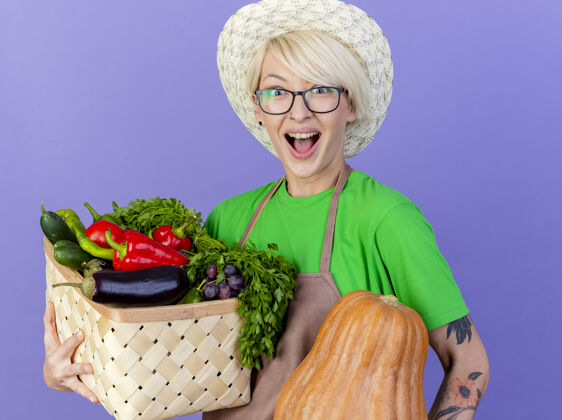 蔬菜一位年轻的园丁 围着围裙 戴着帽子 手里拿着装满蔬菜的箱子头发花园帽子