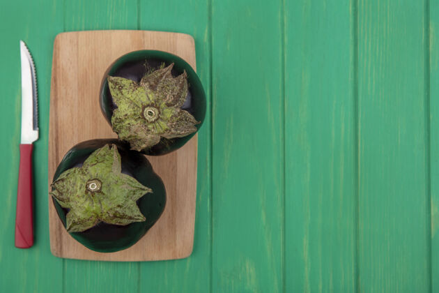 板顶视图复制空间黑色茄子与一个绿色背景上的砧板刀食物空间视图