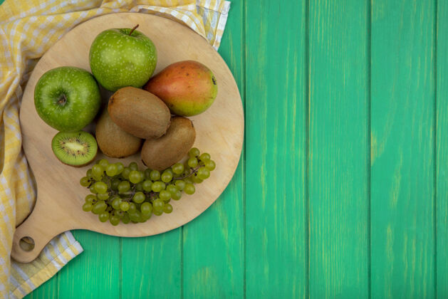 观点顶视图复制空间绿色的苹果与猕猴桃 绿色的葡萄和梨上的立场与黄色方格毛巾上的绿色背景水果顶部苹果