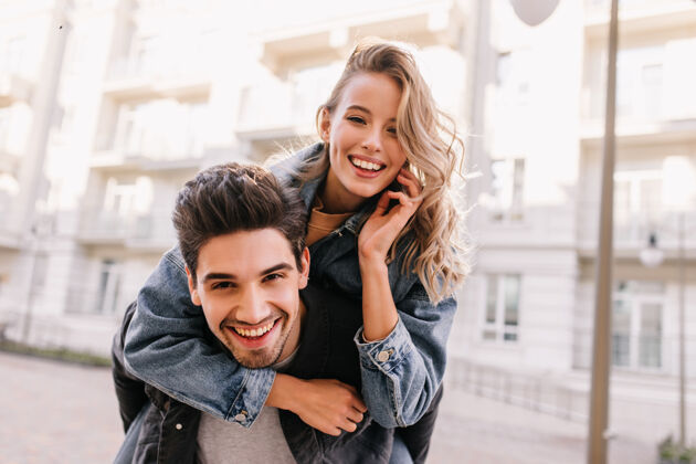 肖像穿着牛仔夹克的女孩拥抱男朋友微笑的白人夫妇在街上合影人乐趣关系