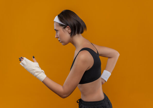 运动员身穿运动服的年轻健身女士戴着头巾在橘色的墙壁上奔跑训练人冲刺头带