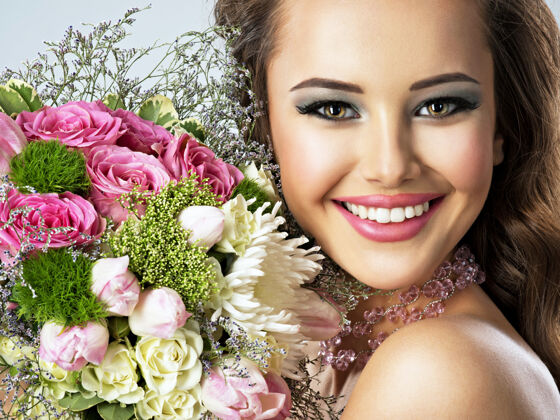 魅力手捧鲜花的美丽快乐女孩的特写肖像年轻迷人的女人捧着春天的花束化妆肖像新鲜