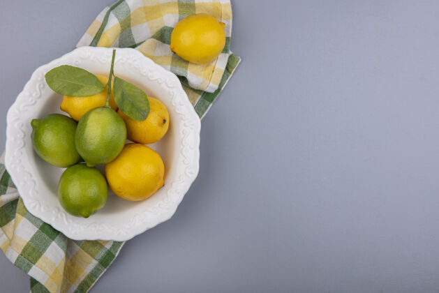 复制顶视图复制空间柠檬与柠檬在一个黄色格子毛巾上的灰色背景板空间上衣酸橙