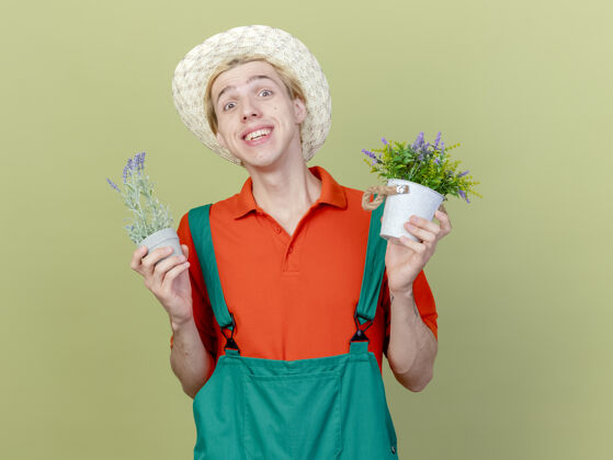 光年轻的园丁 穿着连体衣 戴着帽子 手里拿着盆栽植物锅帽子花园