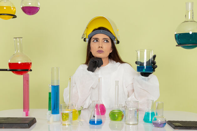 医生前视图穿着特殊防护服的女化学家在绿色表面上处理溶液溶液化学家实验室外套