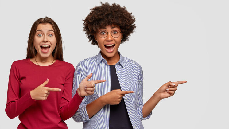 指标开朗的混血女孩有搞笑快乐的表情 站得很近 用食指在空白处标明广告精彩的地方多元文化卖家牙齿室内显示