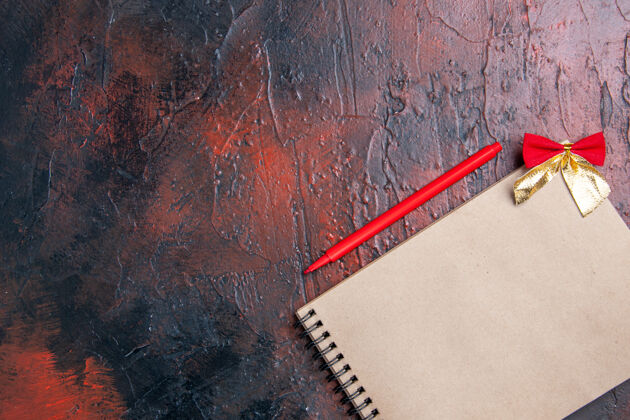 粗糙顶视图红色笔一个小蝴蝶结记事本在暗红色表面与复制空间生锈古董笔