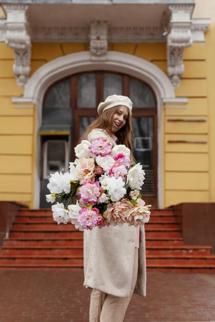 季节美丽的女子手持花束户外侧视图开花城市花