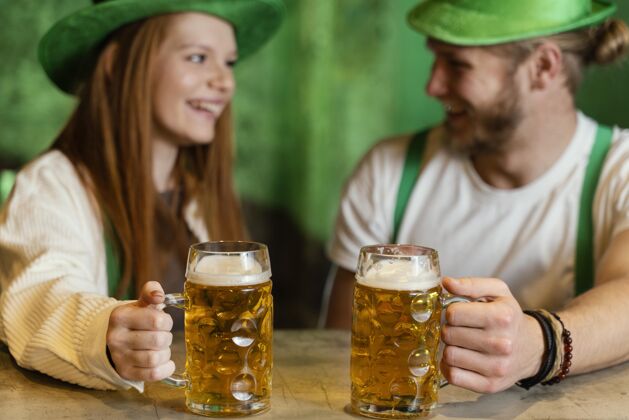三叶草笑脸情侣在酒吧喝饮料庆祝圣帕特里克节帽子活动绿色
