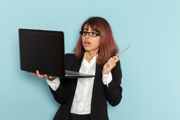 浅蓝色正面图：穿着西装的女上班族在浅蓝色的表面上使用笔记本电脑严格笔记本电脑女商人
