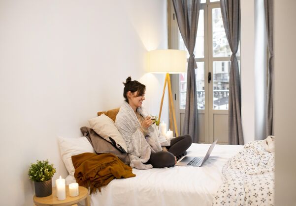 斯堪的纳维亚风格坐在笔记本电脑旁看电视节目的女人房间舒适舒适