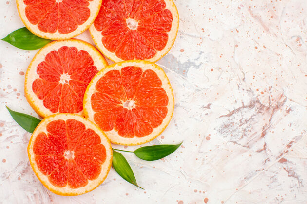 柑橘顶视葡萄柚片与叶片上的裸体表面与复制空间顶部新鲜葡萄柚