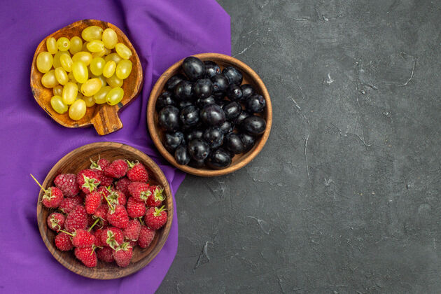 碗顶视图树莓黑色和黄色葡萄在碗上紫色披肩上黑暗孤立的表面自由空间黑莓披肩顶部