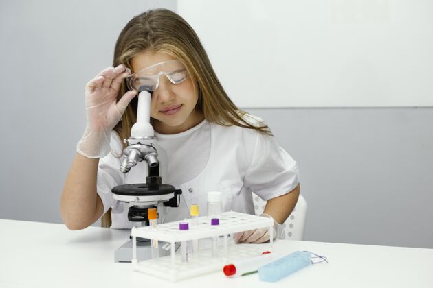孩子年轻女科学家使用显微镜的前视图水平青年化学