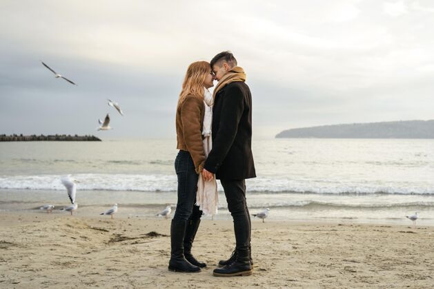 户外爱的年轻夫妇在冬天的海边牵手户外女人情侣