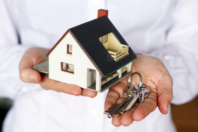 房子拿着钥匙和房子模型的人销售金融房子模型