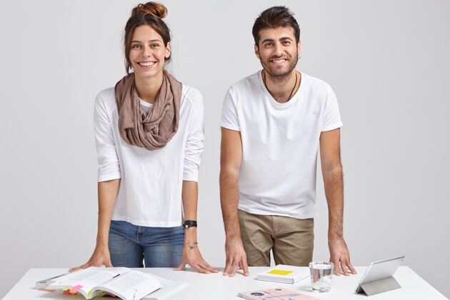 市场营销快乐的年轻男女学生倚在桌子旁的照片同事合作桌子
