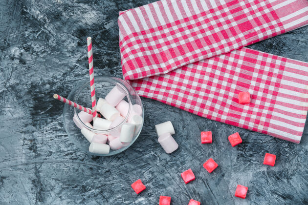 特写平铺棉花糖和甘蔗在罐子里与糖果和红色方格桌布在深蓝色大理石表面水平面粉木头糖