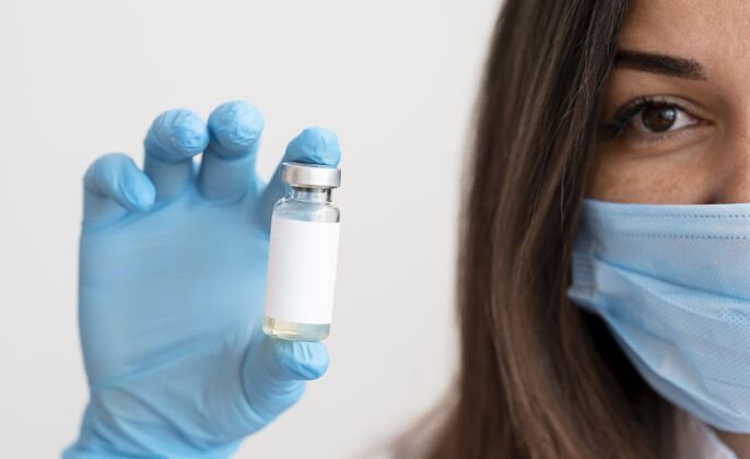 健康戴着医用口罩拿着疫苗接受者的女人诊所保健预防
