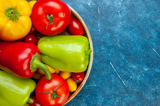 胡椒上半视图蔬菜樱桃西红柿不同颜色的甜椒西红柿放在蓝色桌子上的木盘上复制的地方蔬菜樱桃铃铛胡椒