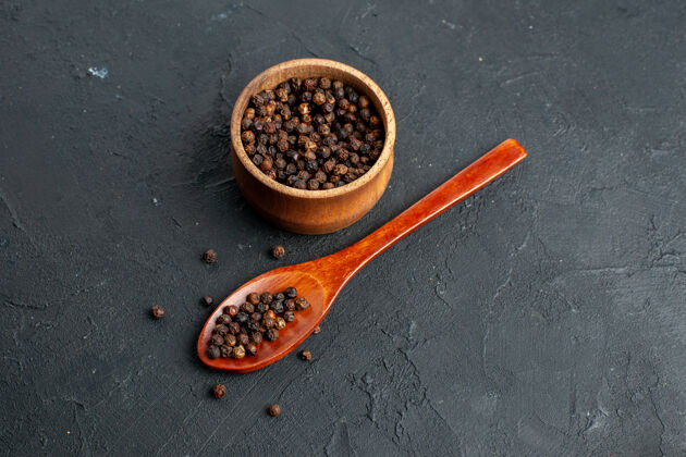 香料顶视图黑胡椒碗木制勺子在黑色表面豆类香味观点