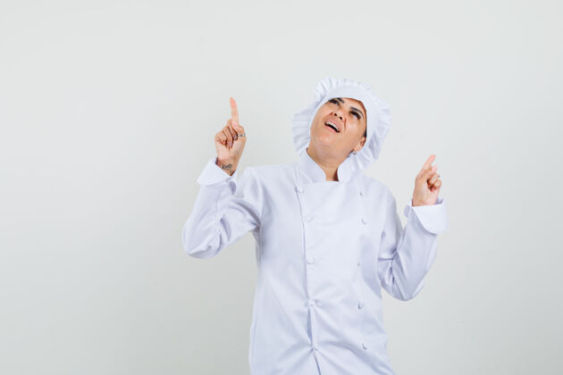 新鲜穿着白色制服的女厨师指着头 看起来很梦幻制服烹饪向上