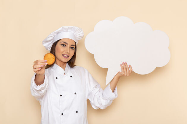 工作身穿白色厨师服的年轻女厨师手持饼干 在浅白的墙上挂着白色的招牌无辜女性工作