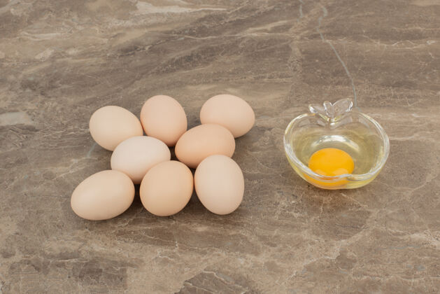 好吃的在大理石表面的盘子上放几个鸡蛋和生鸡蛋鸡蛋食物蛋黄