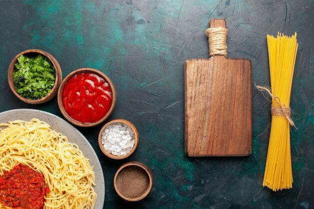 调味品顶视图煮熟的意大利面食与肉和不同的调味品在深蓝色的表面食物意大利插头