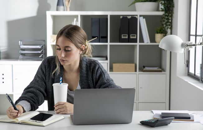 商业女性中等身材的女人在笔记本上写字笔记本电脑职业技术
