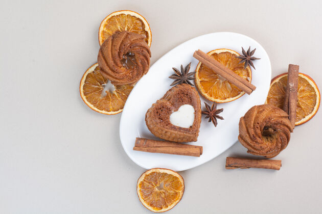 甜点各种各样的蛋糕 橘子片 丁香和肉桂放在白色盘子里美味蛋糕橘子