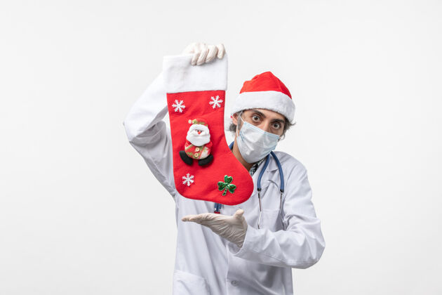 冠状病毒正面图白色墙壁上戴着大节日袜子的男医生-圣诞病毒风景男人肖像